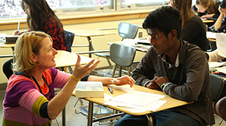 A teacher talks with an English language learning student about an essay he is writing.