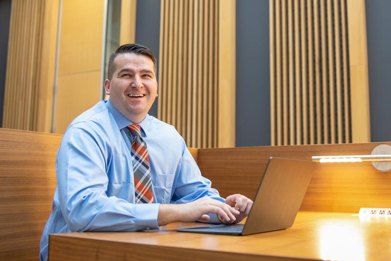 Ecampus student Chris Burke, smiling, with his hands over a laptop