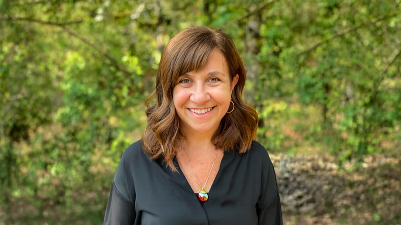 A picture of Lisa Templeton, smiling in a wooded area.