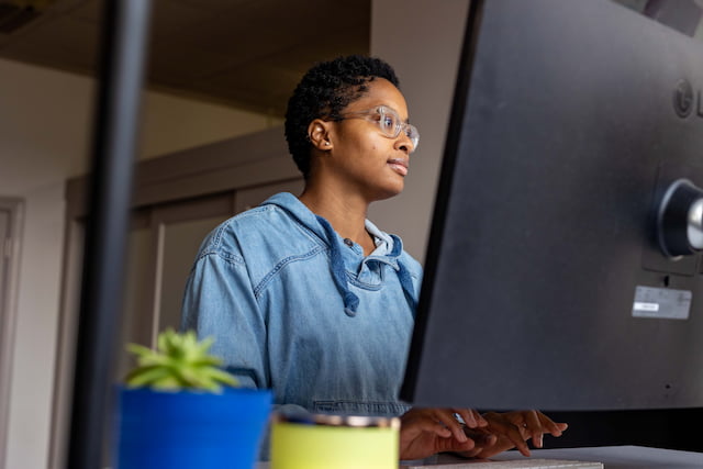 Ravonne Byrd wears glasses as she looks intently toward a computer screen.