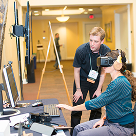 Ecampus multimedia developer Nick Harper looks at a computer screen while helping an Ecampus instructor to use a virtual reality headset.