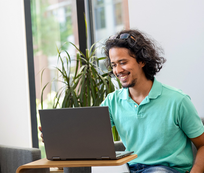 Joshua Chan Burgos, OSU student, sitting at a desk with a laptop