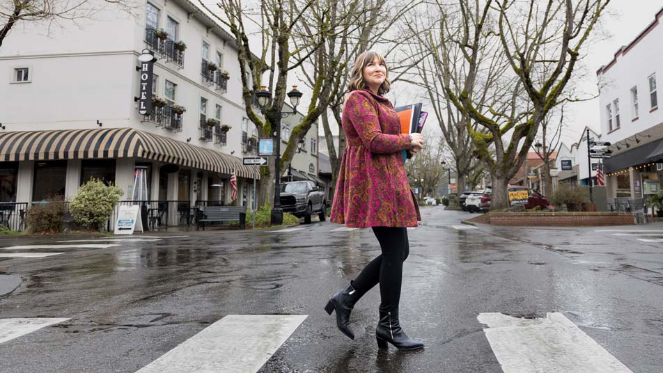 Kaitlin Lee, who earned a bachelor's degree in business administration online from Oregon State University, walks in a crosswalk in an urban environment while she smiles.