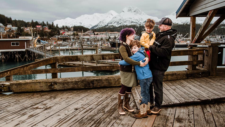 Tommy Sheridan, who earned a Professional Science Master’s in Fisheries and Wildlife Administration through Oregon State University Ecampus, stands on a dock with his family in Cordova, Alaska.
