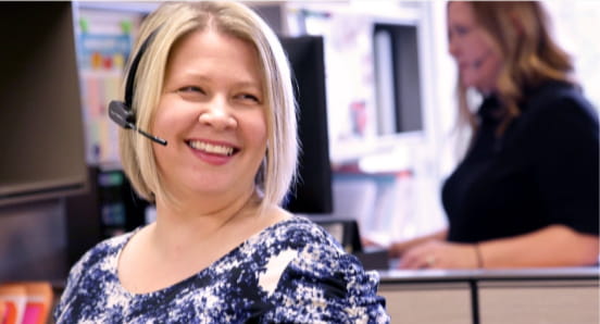 An Ecampus enrollment specialist in an office space wearing a phone headset.