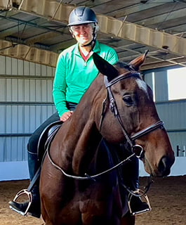 Yvette Gibson, rangeland sciences instructor riding a brown horse inside a covered arena