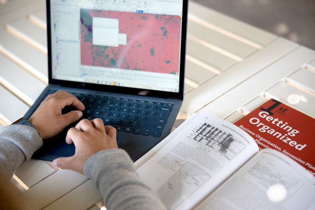 A person's hands are seen typing on a laptop computer