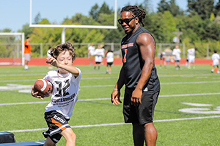 Jacquizz Rodgers, human development and family sciences graduate, watches a youth football player go through a drill at the Jacquizz Rodgers Football Camp