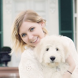 Erin Traub smiles at the camera while holding a Goldendoodle puppy