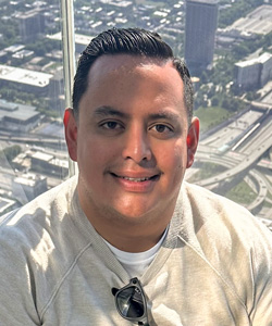 Isai Espinoza smiles at the camera in front of a bright window
