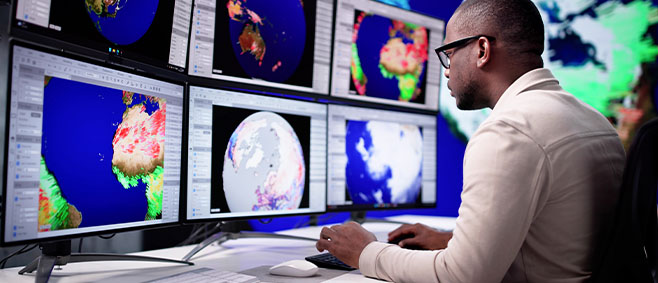Data scientist analyzing global climate maps on multiple monitors, reviewing patterns and environmental data