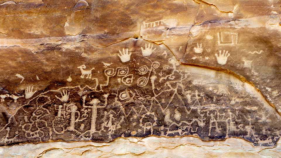 Rock panel displaying ancient petroglyphs, including handprints and stylized human and animal forms
