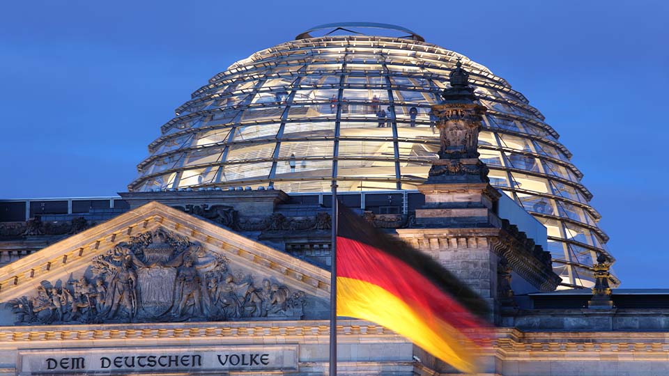 The Reichstag building in Berlin with German flag flying in foreground