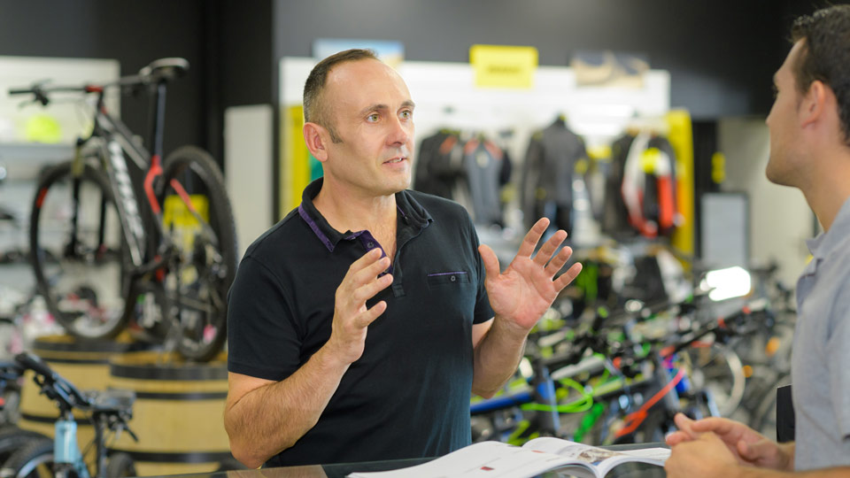 A man in a bike shop speaking to a customer