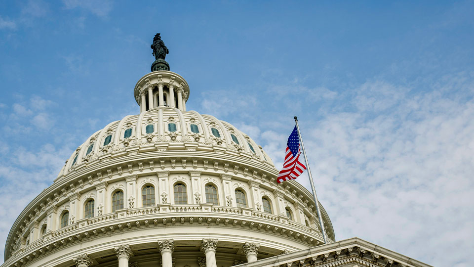 Close-up of the United States Capitol building dome with American flag flying in foreground