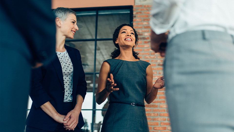 Women in business attire talking with other people at event-like setting
