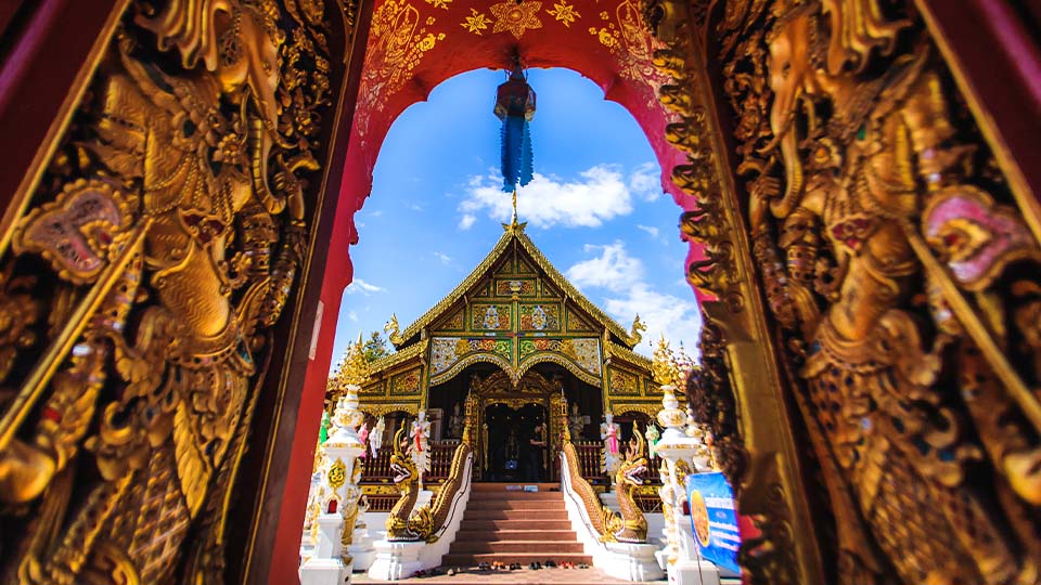 View of Wat Ming Muang temple in Thailand with golden artwork in foreground