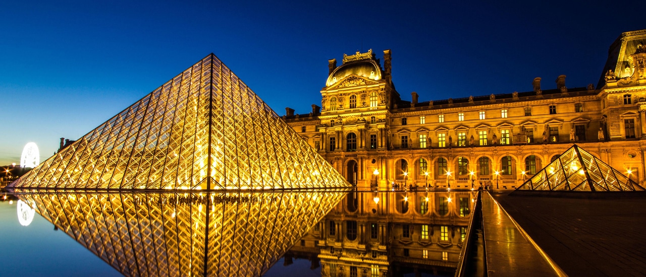 Mus&eacute;e du Louvre illuminated at night with pyramid in foreground reflecting in water
