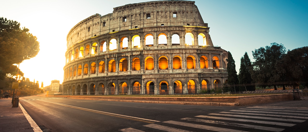 The Colosseum in Rome illuminated by evening sunlight with street in foreground