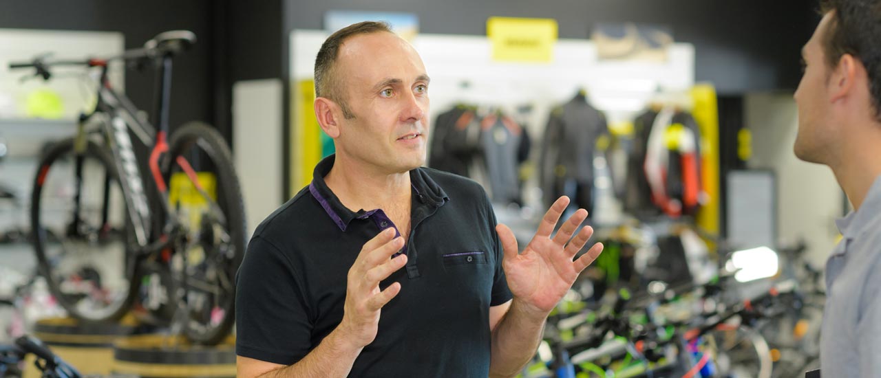 A man in a bike shop speaking to a customer