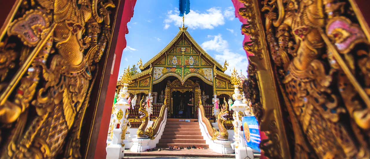 View of Wat Ming Muang temple in Thailand with golden artwork in foreground