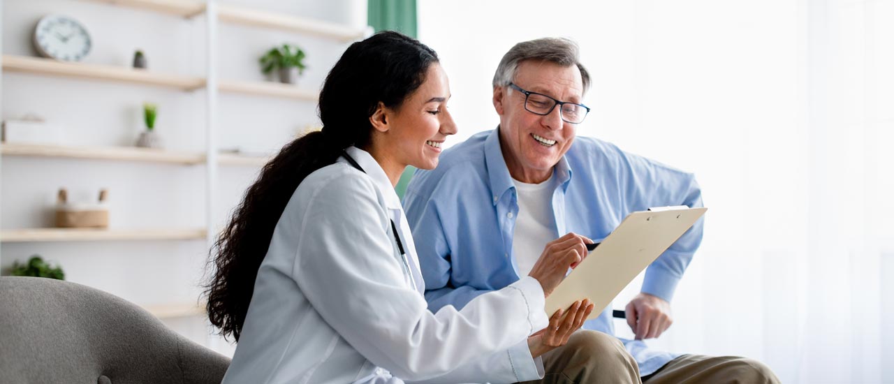 A doctor talks with her patient while pointing out information on a clipboard.