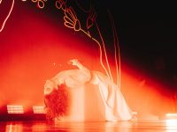 Singer Lorde on stage laying on a box