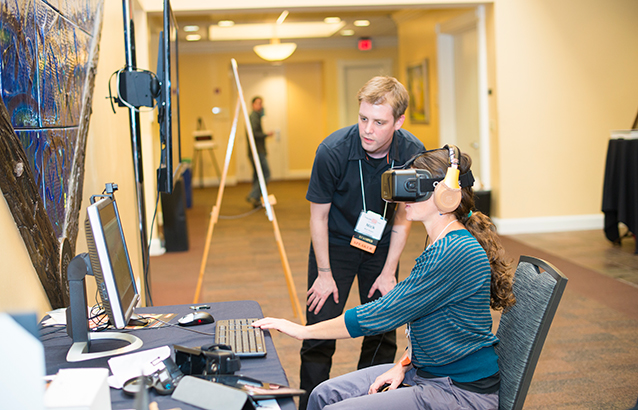 A member of the Oregon State Ecampus staff helps demonstrate a virtual reality assignment to an attendee of the faculty forum event.