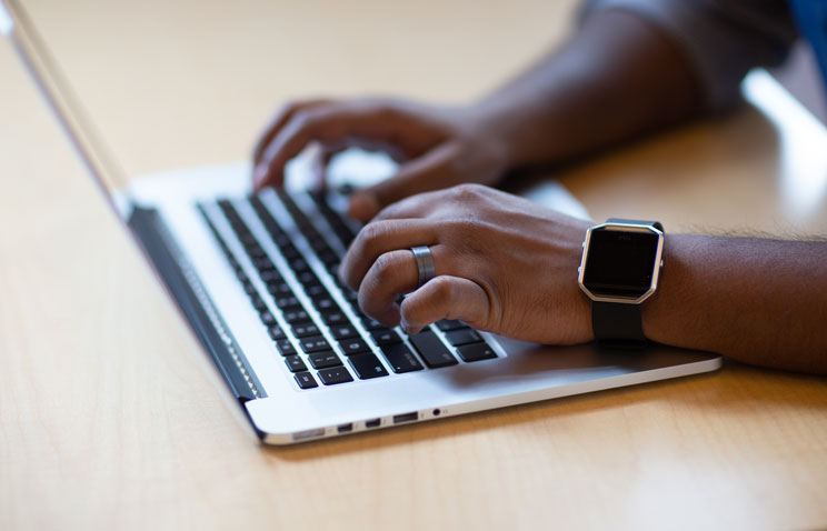 A student types on the keyboard of a slim silver laptop. Financial aid