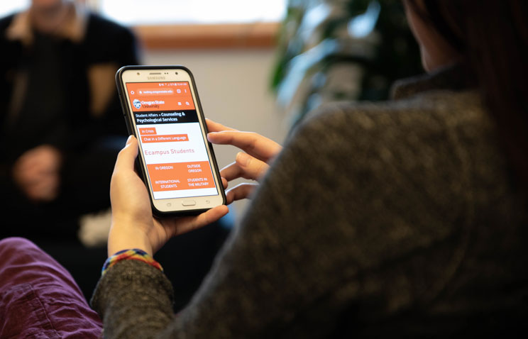 A person uses a smartphone to access Oregon State University's mental health resources online