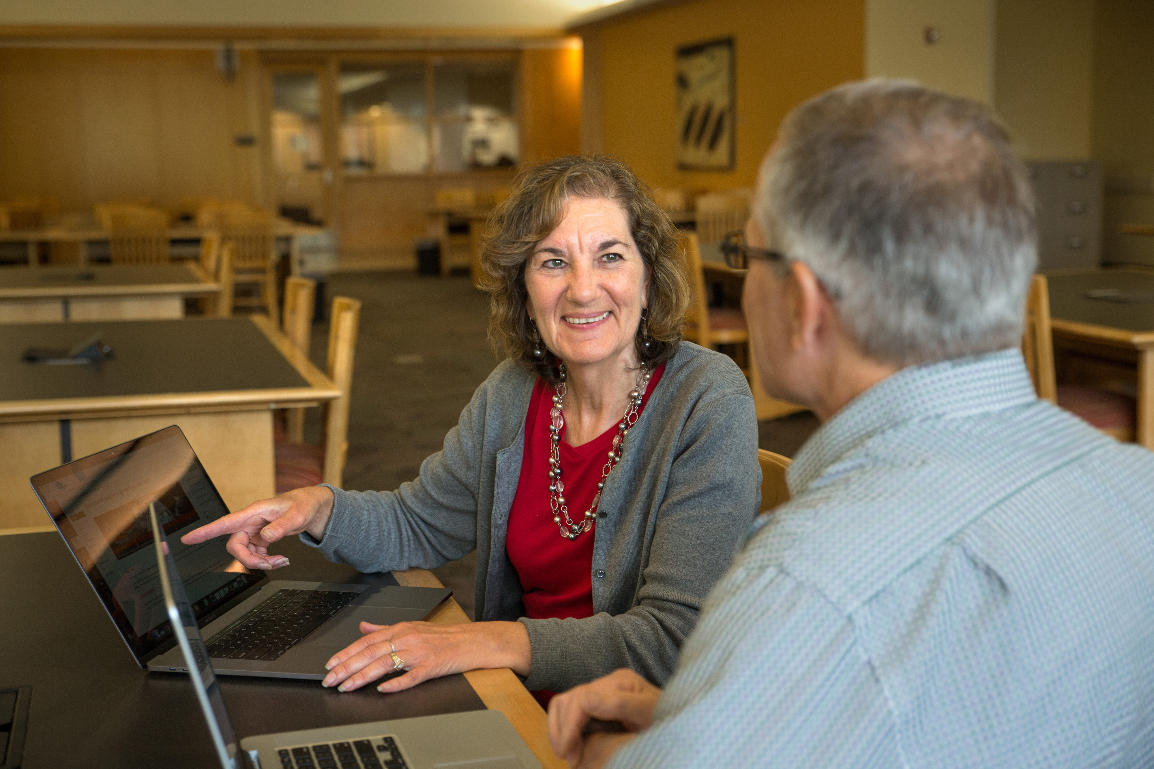 Two people sit together at a table with laptops in front of them and collaborate on instructional design.