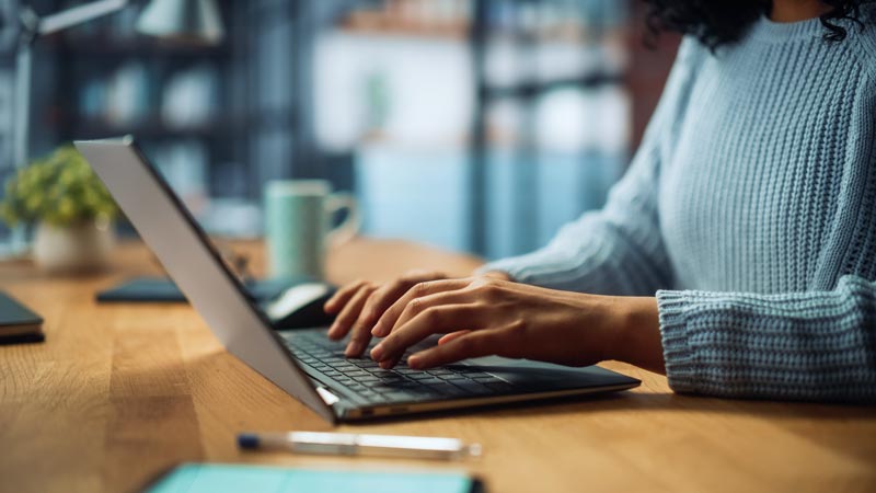 woman's hands typing on a laptop