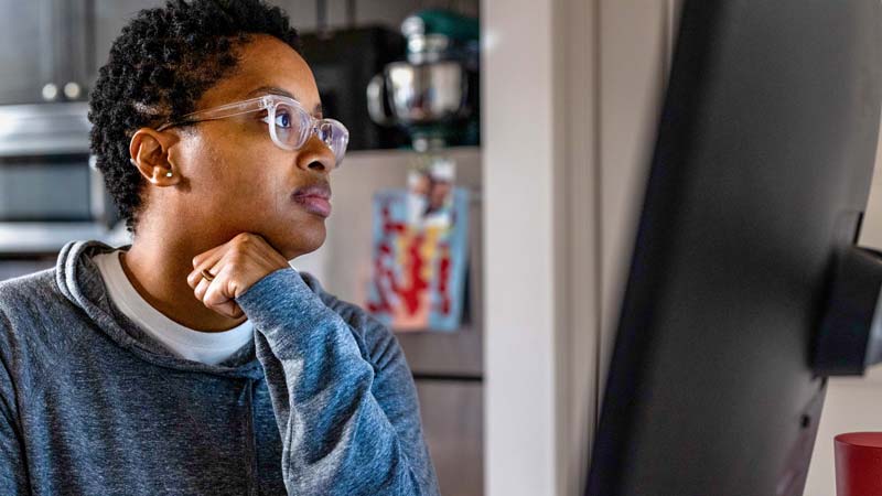 Ravonne Byrd wears glasses as she looks intently toward a computer screen.