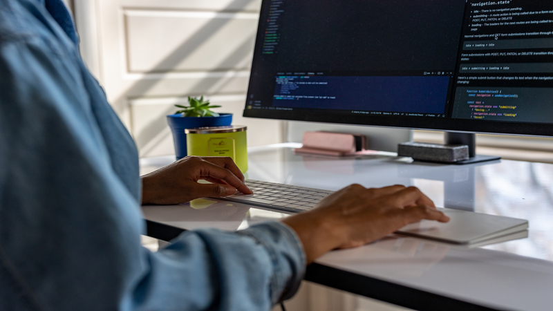 A person at a desk types on a computer.