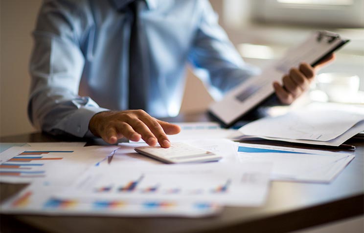 A person sits at a desk while examining paperwork. Economics degree online