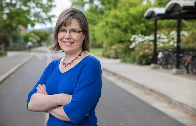 Karen Watté stands in the street with her arms crossed in front of her.