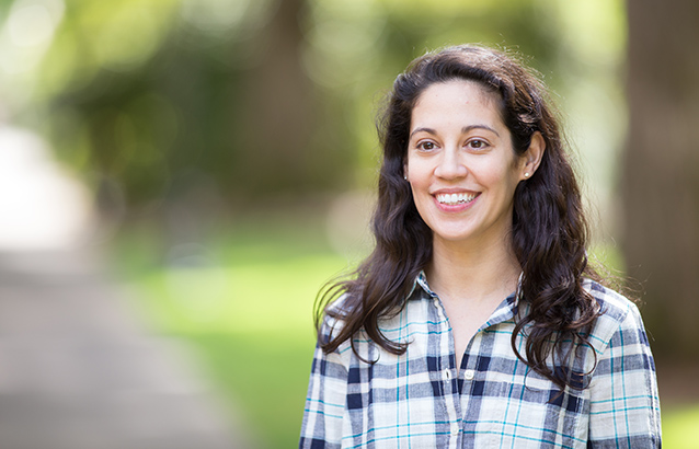 Kristy Trevino faces slightly to her right and smiles. She wears a plaid-patterned black and white shirt.