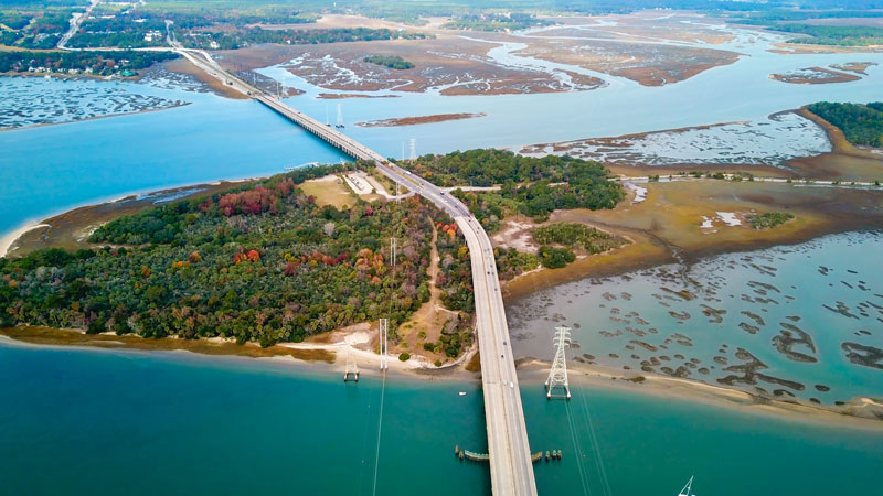 An aerial photo of a coastal peninsula, connected by a large bridge to the north and south.