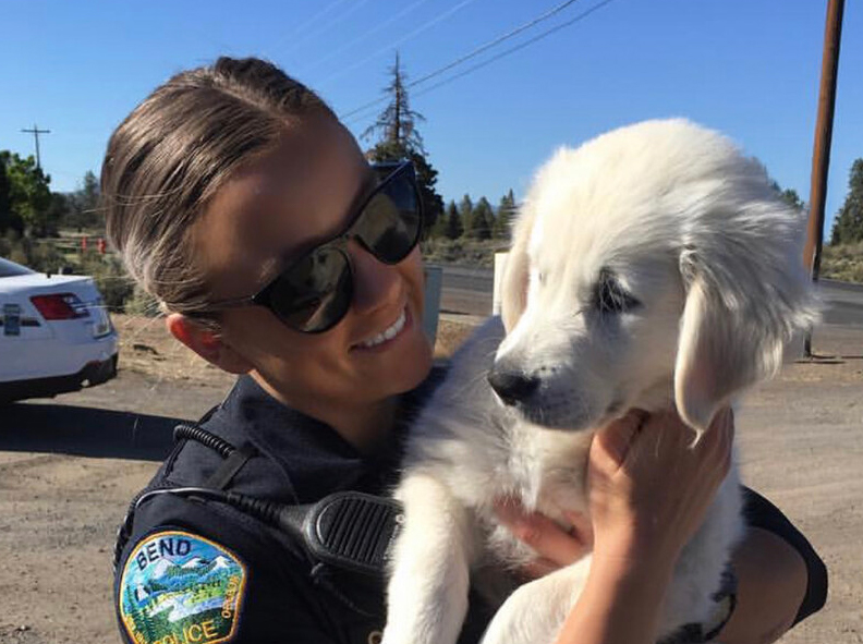 Oregon State University Ecampus graduate Caitlin Brooks, then a police officer in central Oregon, holds a white dog